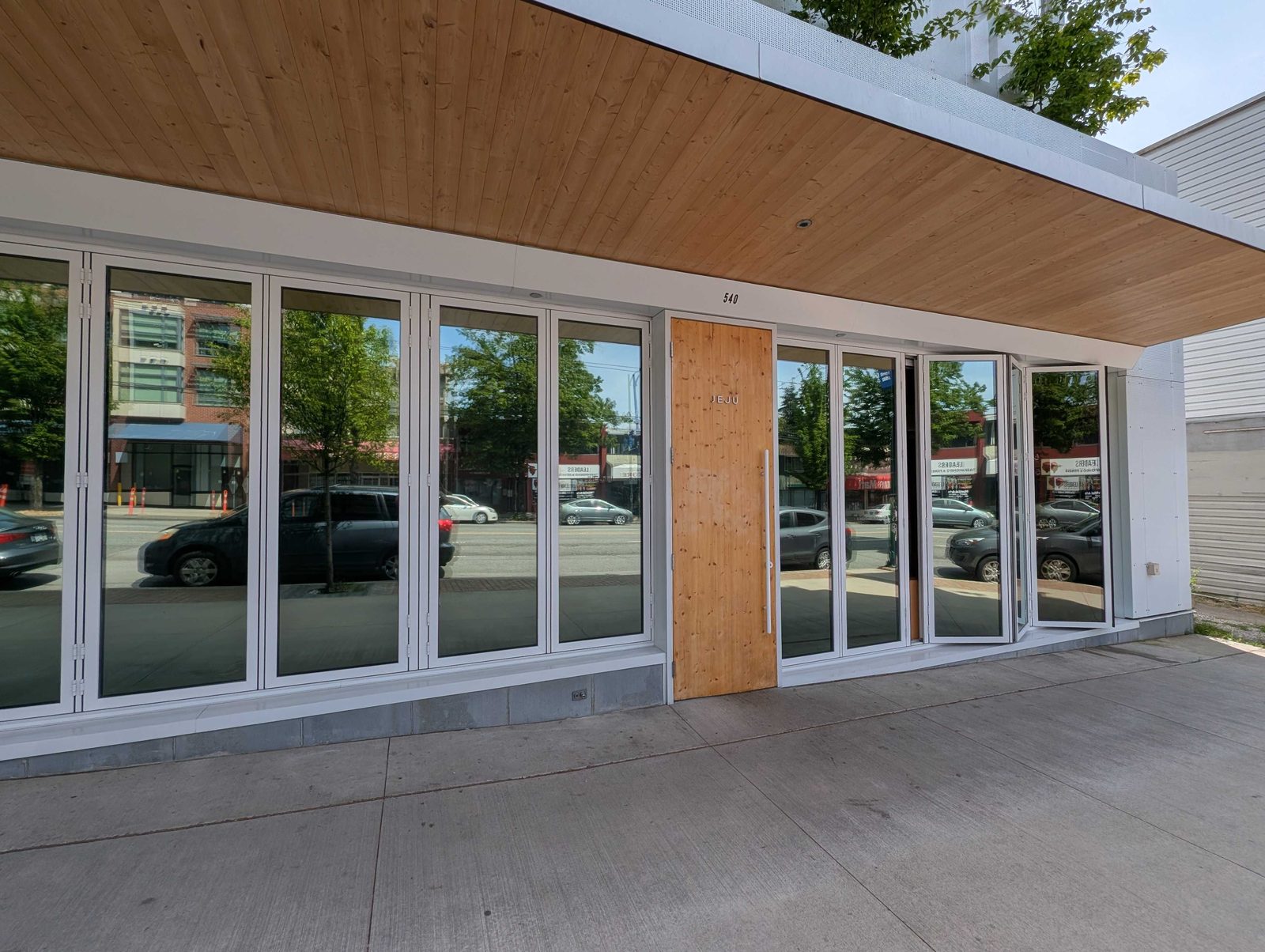 Ecovision installer in brick-red shirt inspecting clear commercial lobby glass after plastic film removal in Vancouver